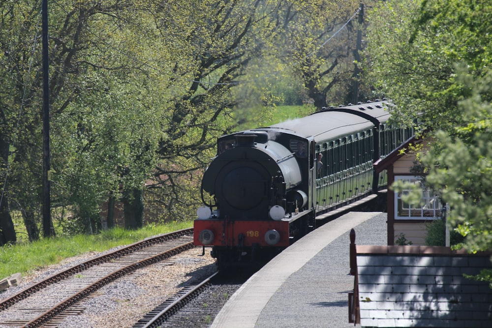 a train traveling down tracks next to a forest