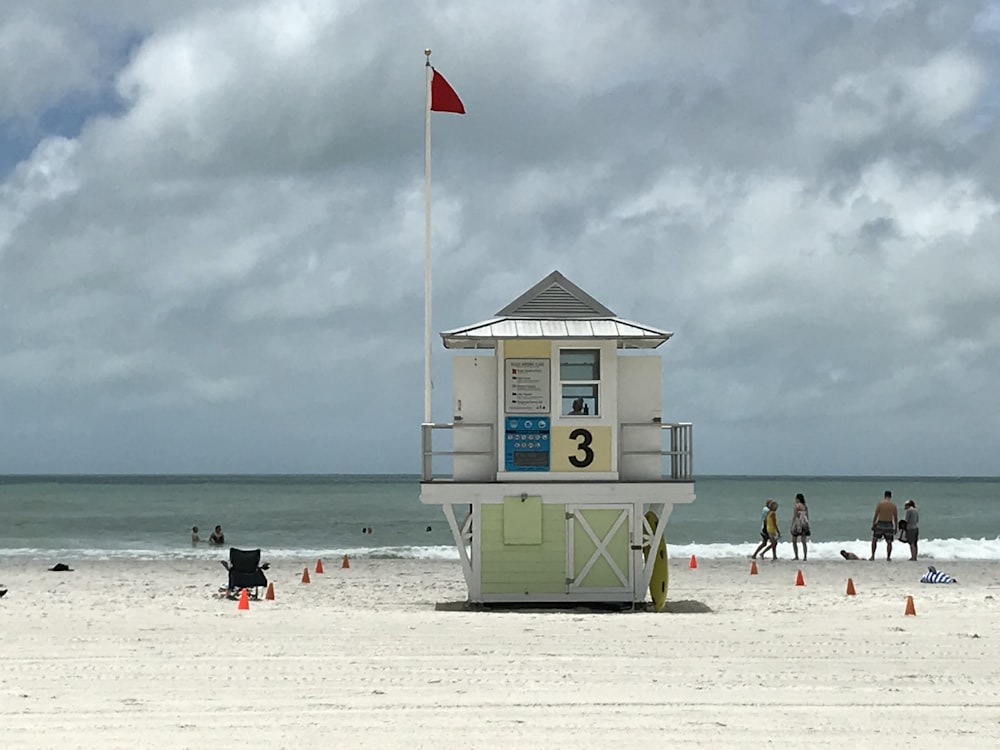 a lifeguard tower on a beach with people walking around