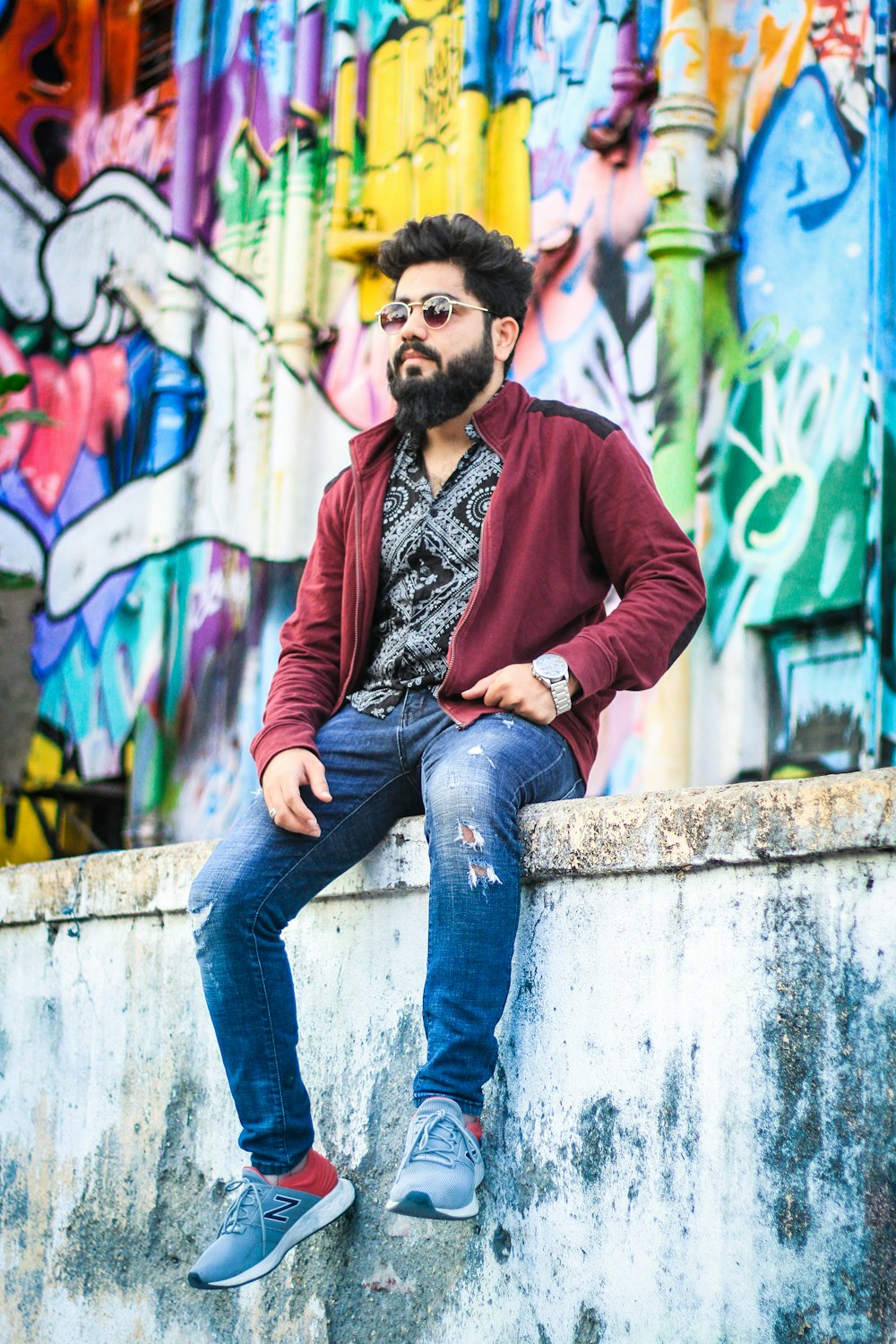 a man with a beard sitting on a wall