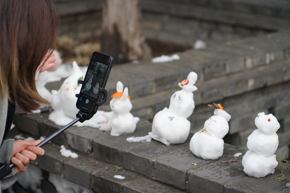 a woman taking a picture of a bunch of snowmen