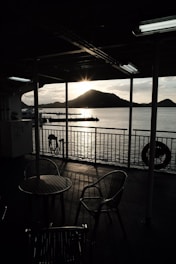 Sunset over Lake Batur seen from a wooden deck with comfortable seating and tribal art accents.