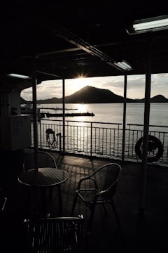 Sunset over Lake Batur seen from a wooden deck with comfortable seating and tribal art accents.