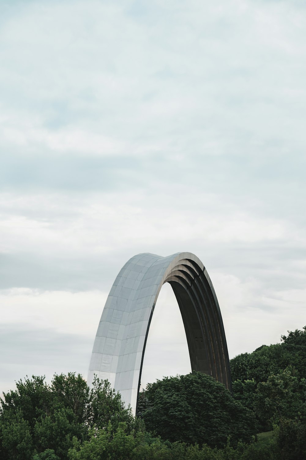 a large metal arch sitting next to a lush green forest