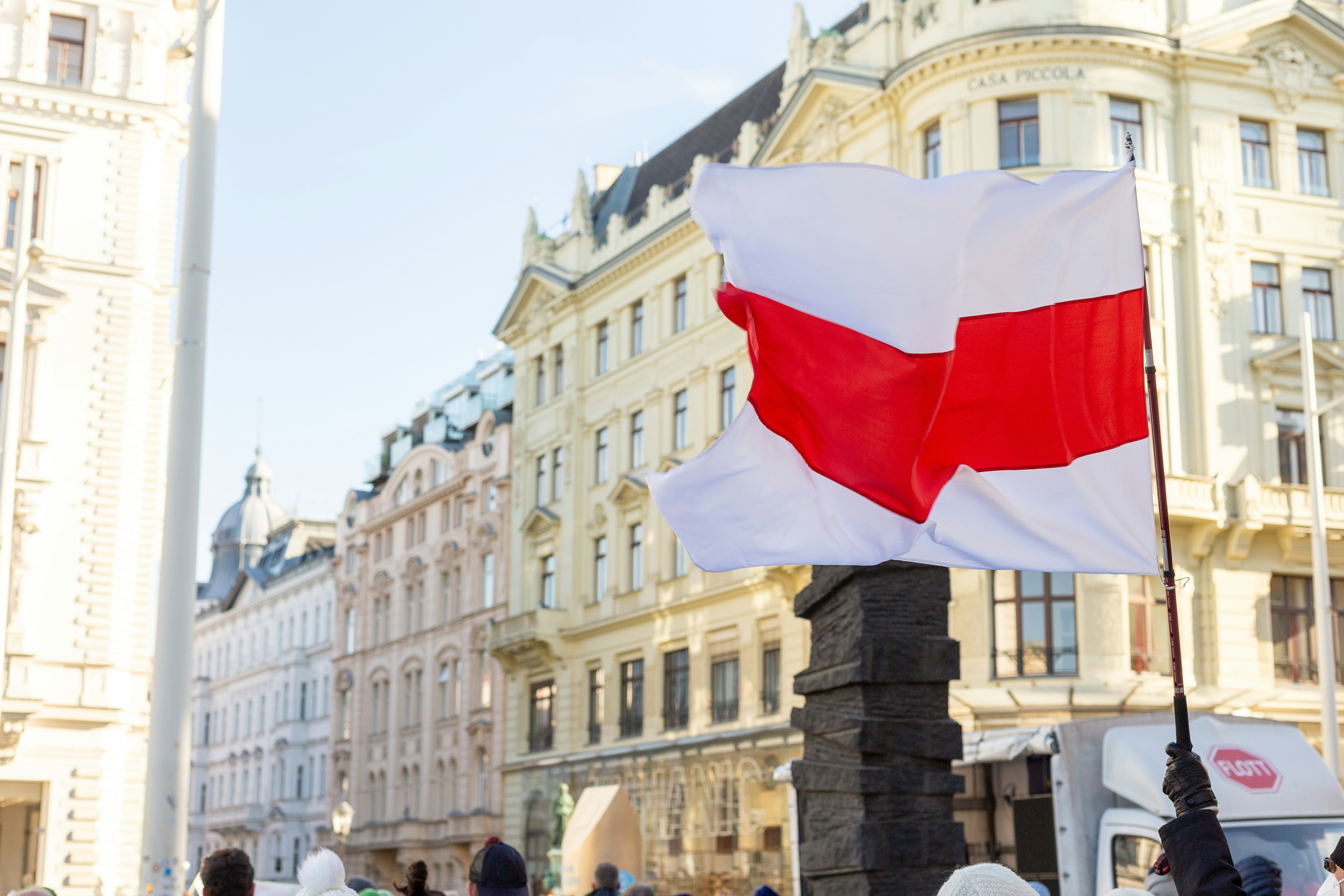 a red and white flag on a pole in front of a building