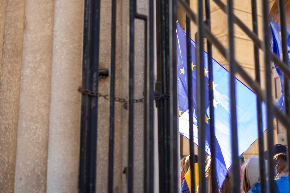 a group of people holding flags behind a gate