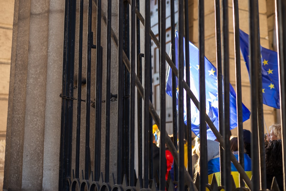 a group of people behind a fence with flags