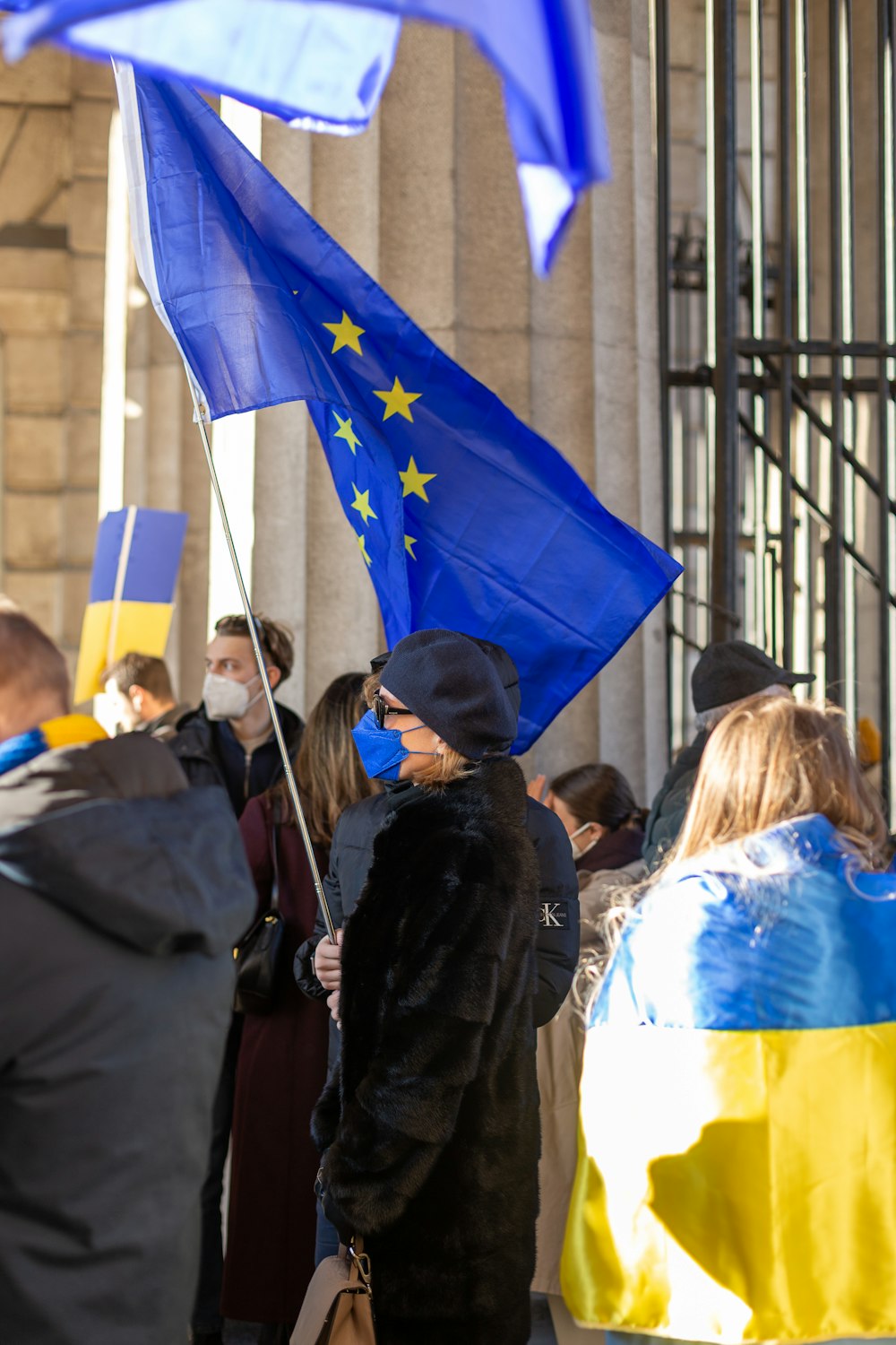 a crowd of people standing around a building with flags