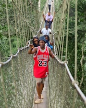 a group of people walking across a suspension bridge