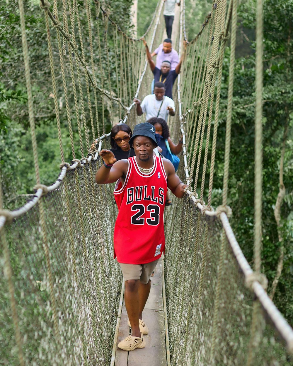 a group of people walking across a suspension bridge