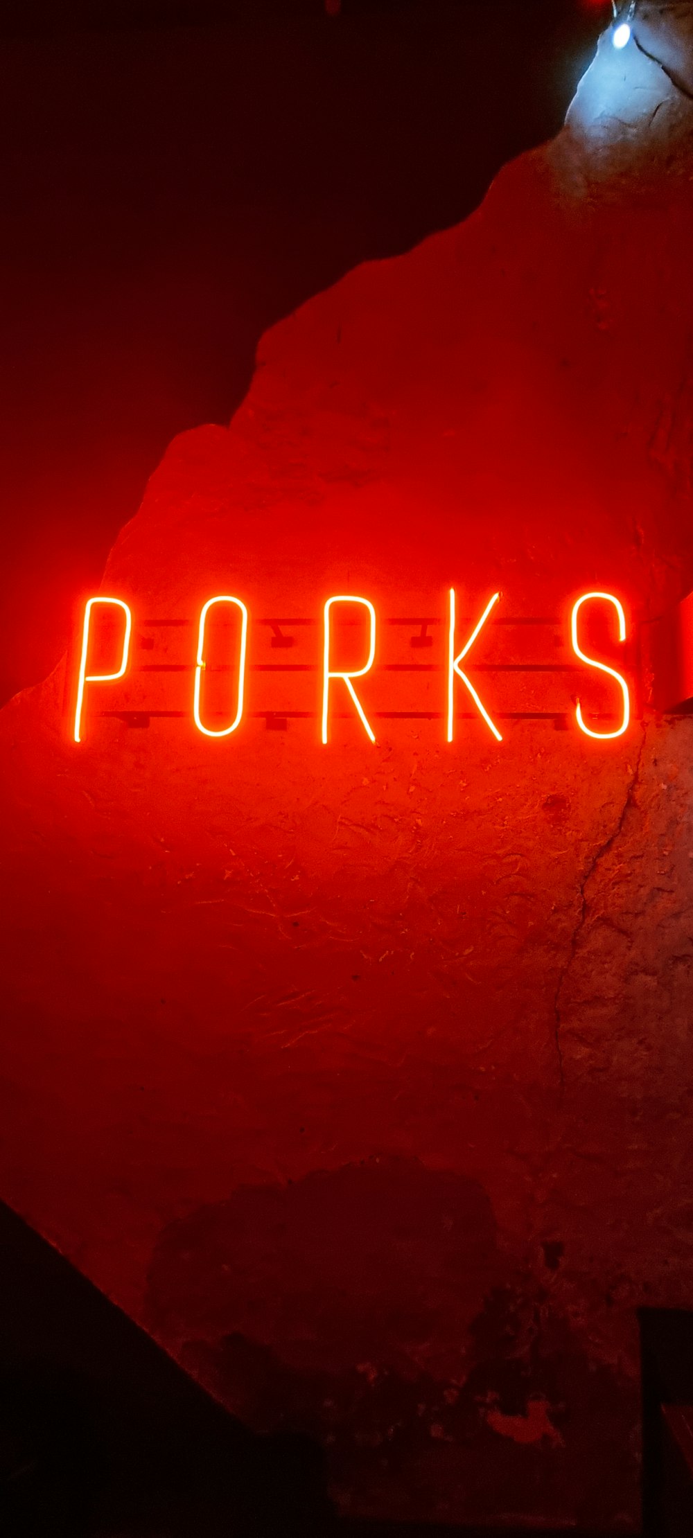 a red neon sign that reads porks
