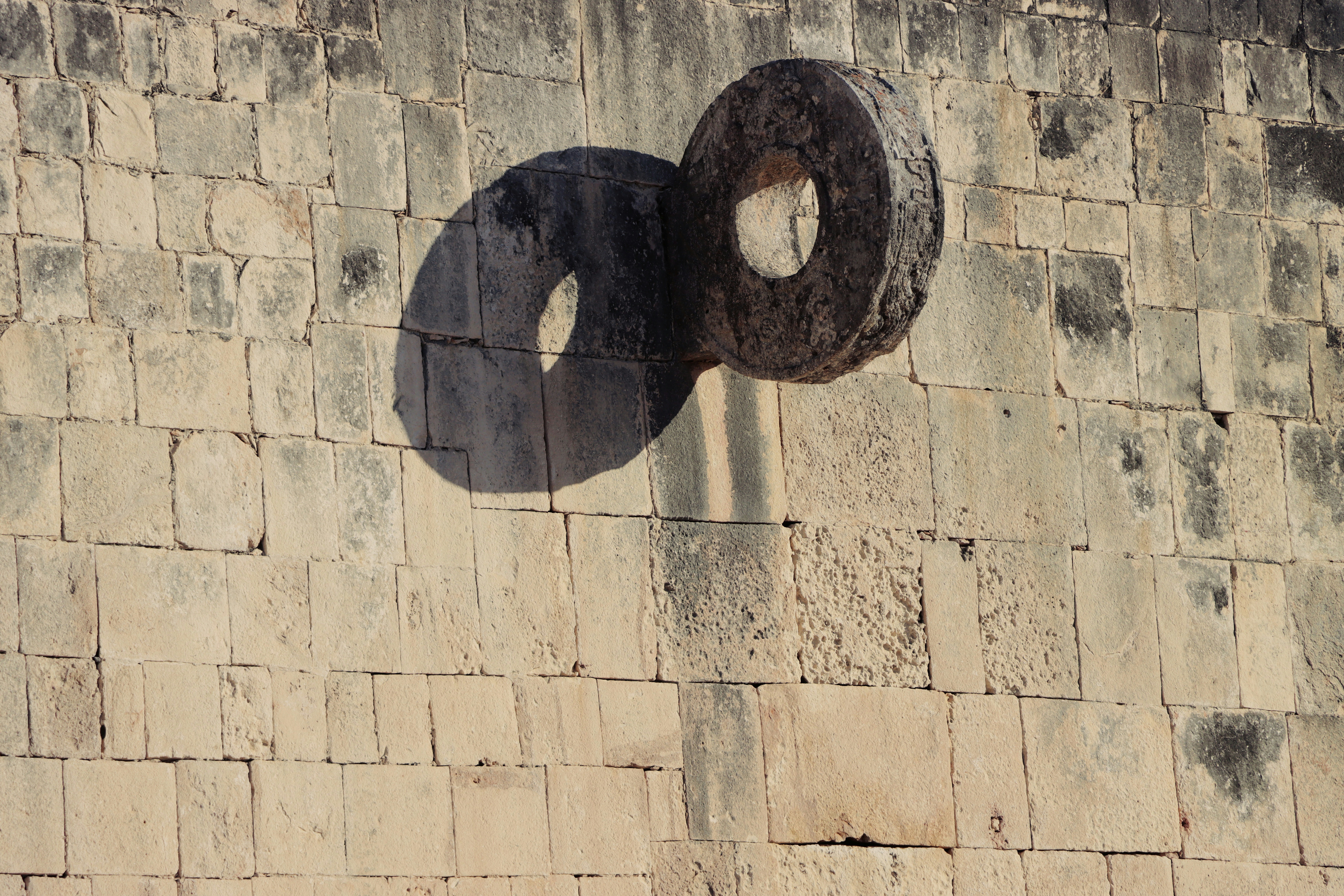 a shadow of a circular object on a brick wall, 