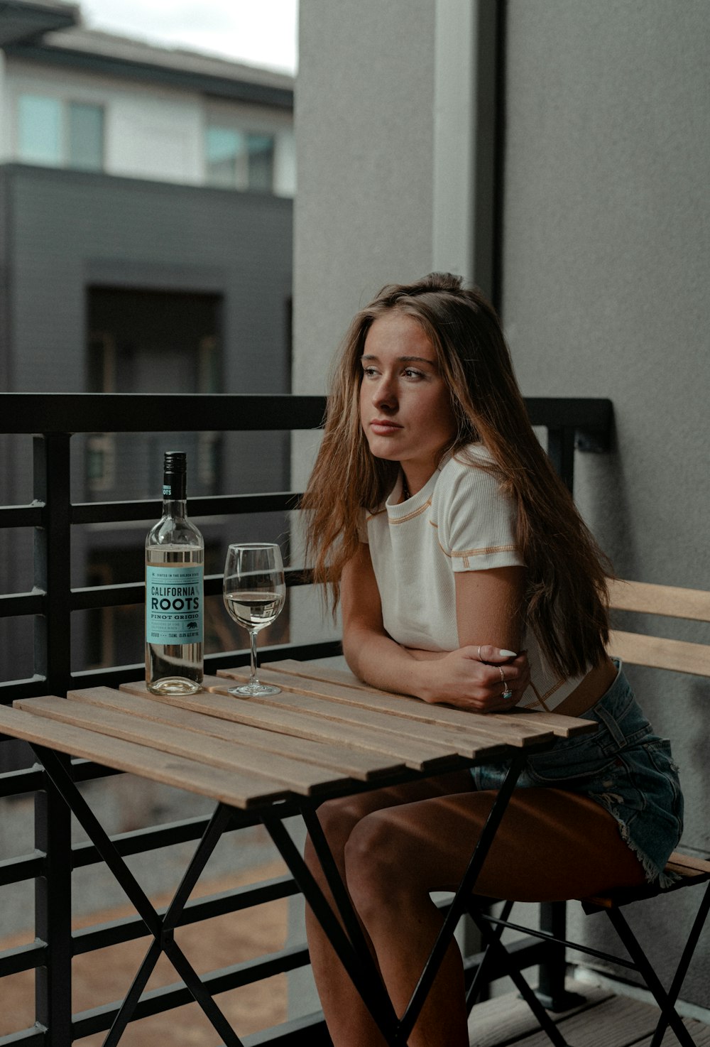 a woman sitting at a table with a bottle of wine