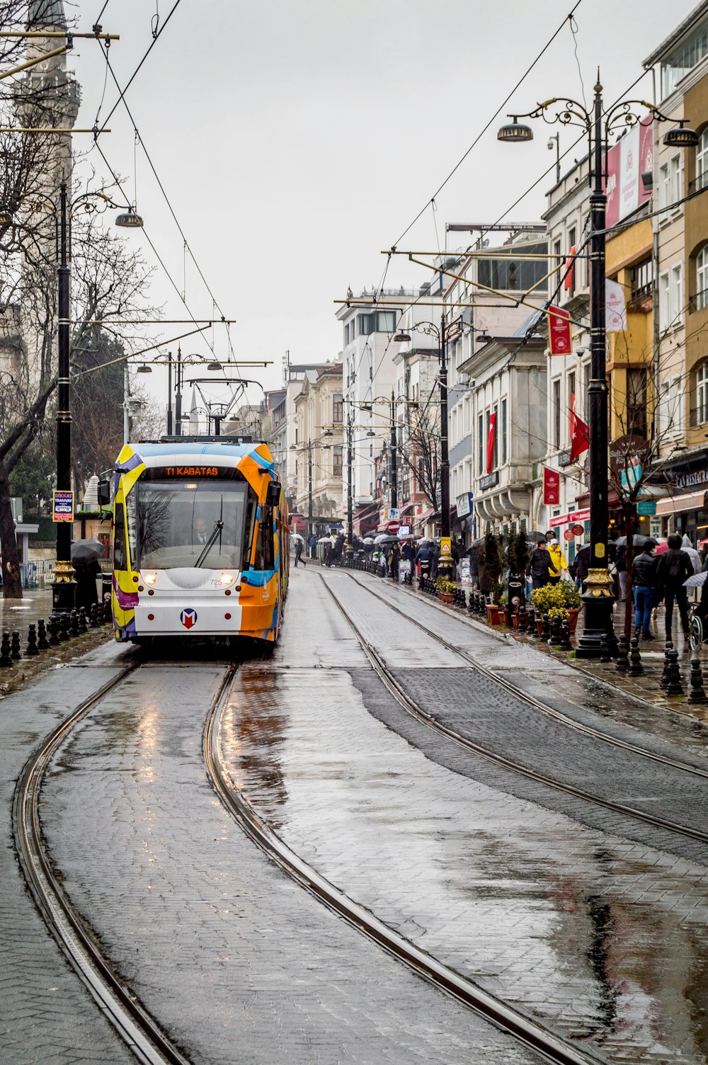 a yellow and white bus driving down a wet street