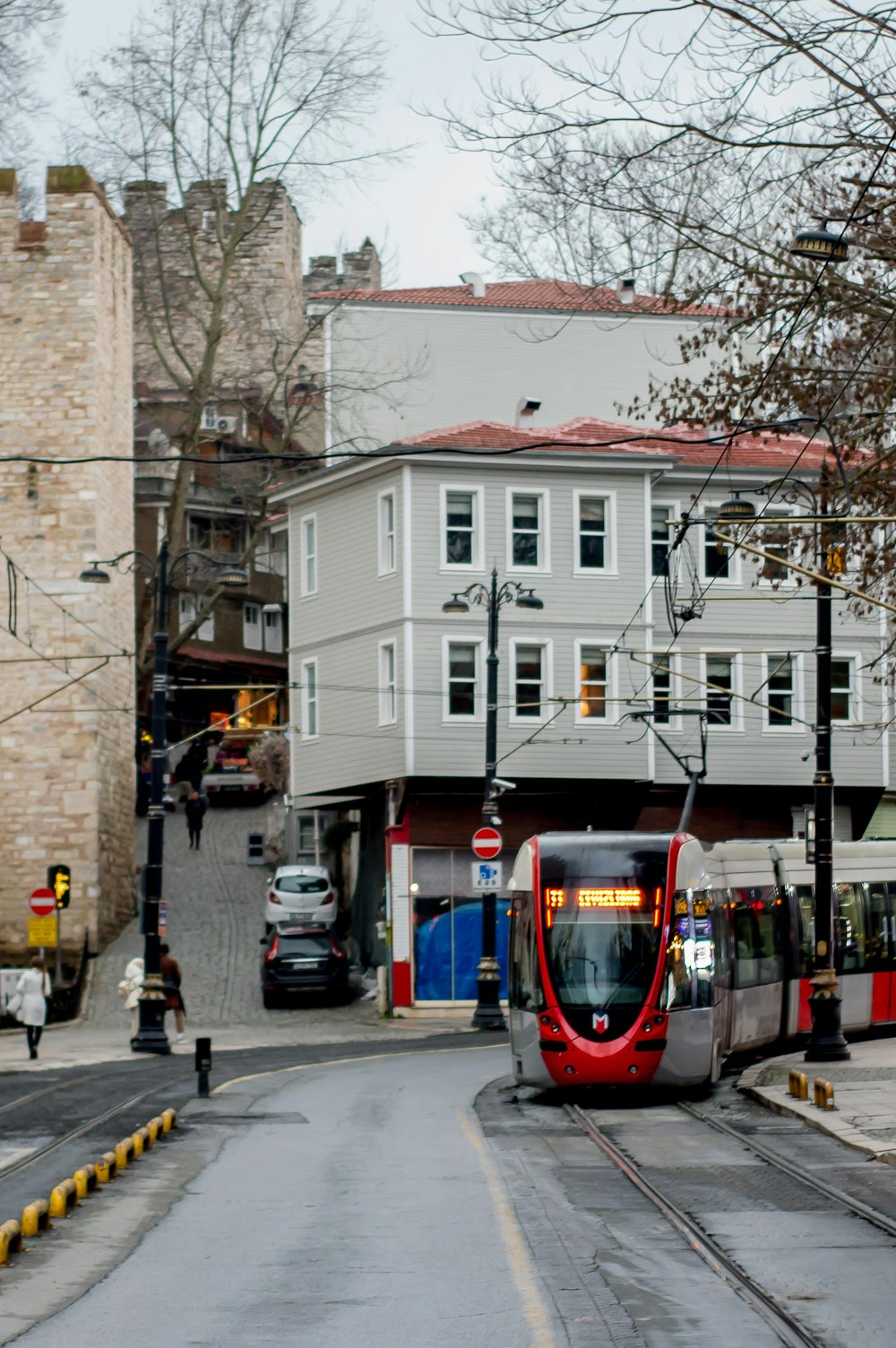 a red and silver train traveling down a street next to tall buildings