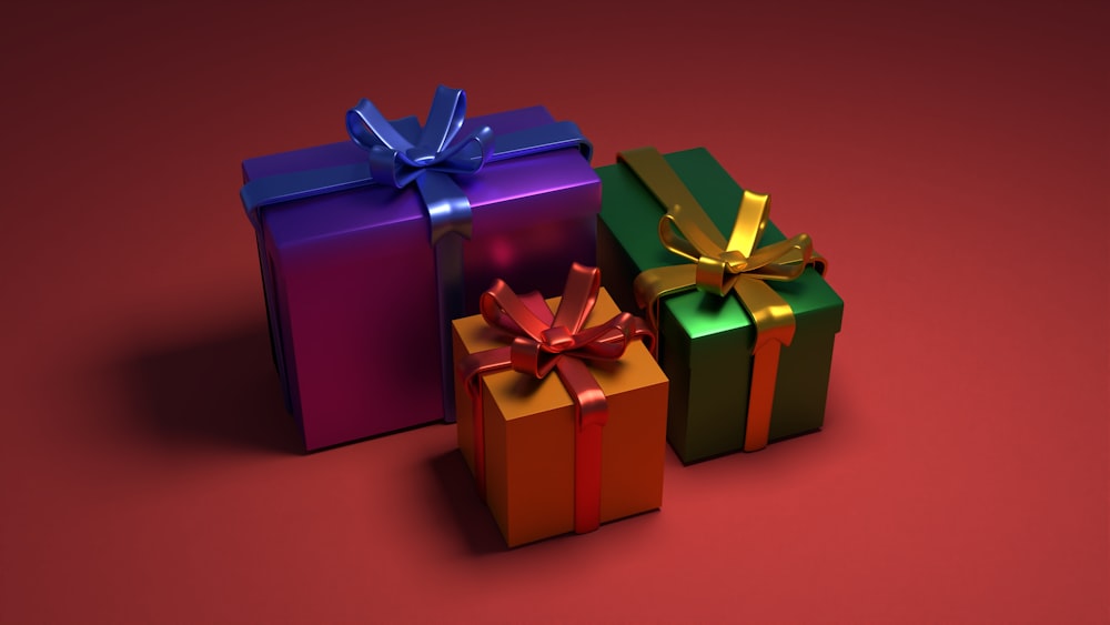 Tres coloridas cajas de regalo con lazos sobre fondo rojo