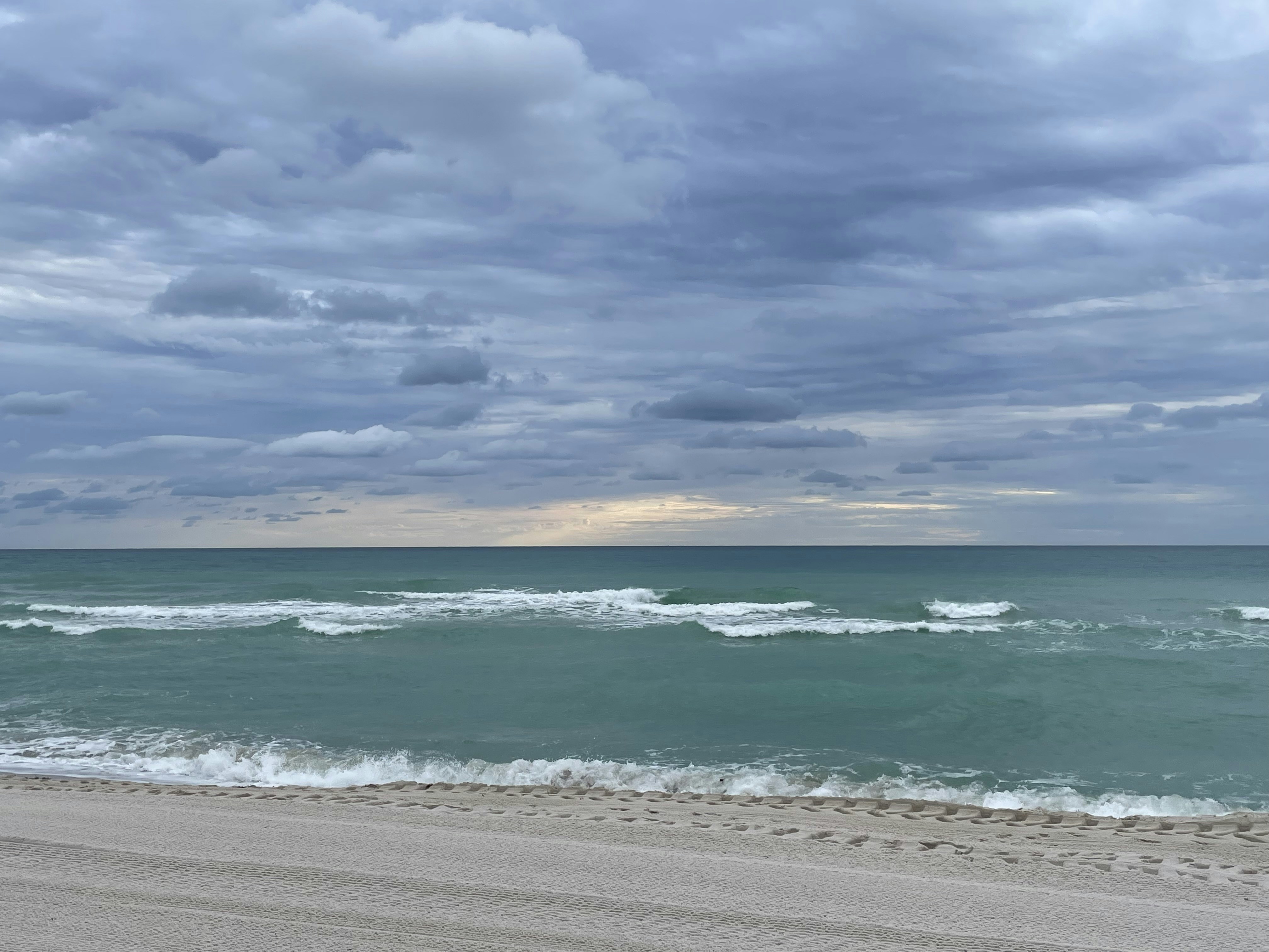 a cloudy day at the beach with a surfboard in the foreground