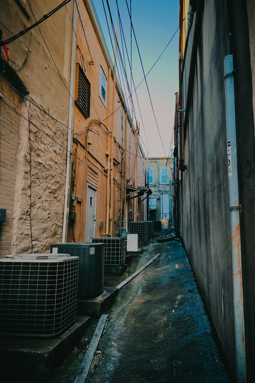 a narrow alley way with air conditioners on both sides