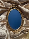 a mirror sitting on top of a satin covered bed