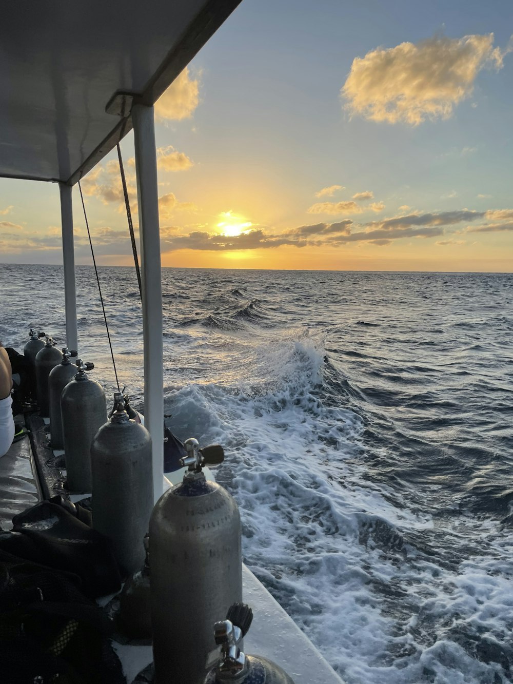 the sun is setting over the ocean on a boat