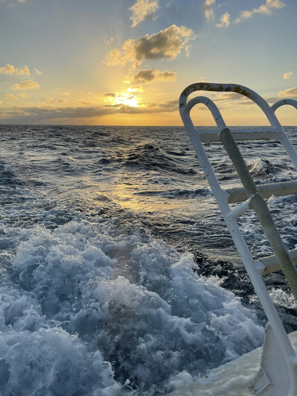 the sun is setting over the ocean on a boat