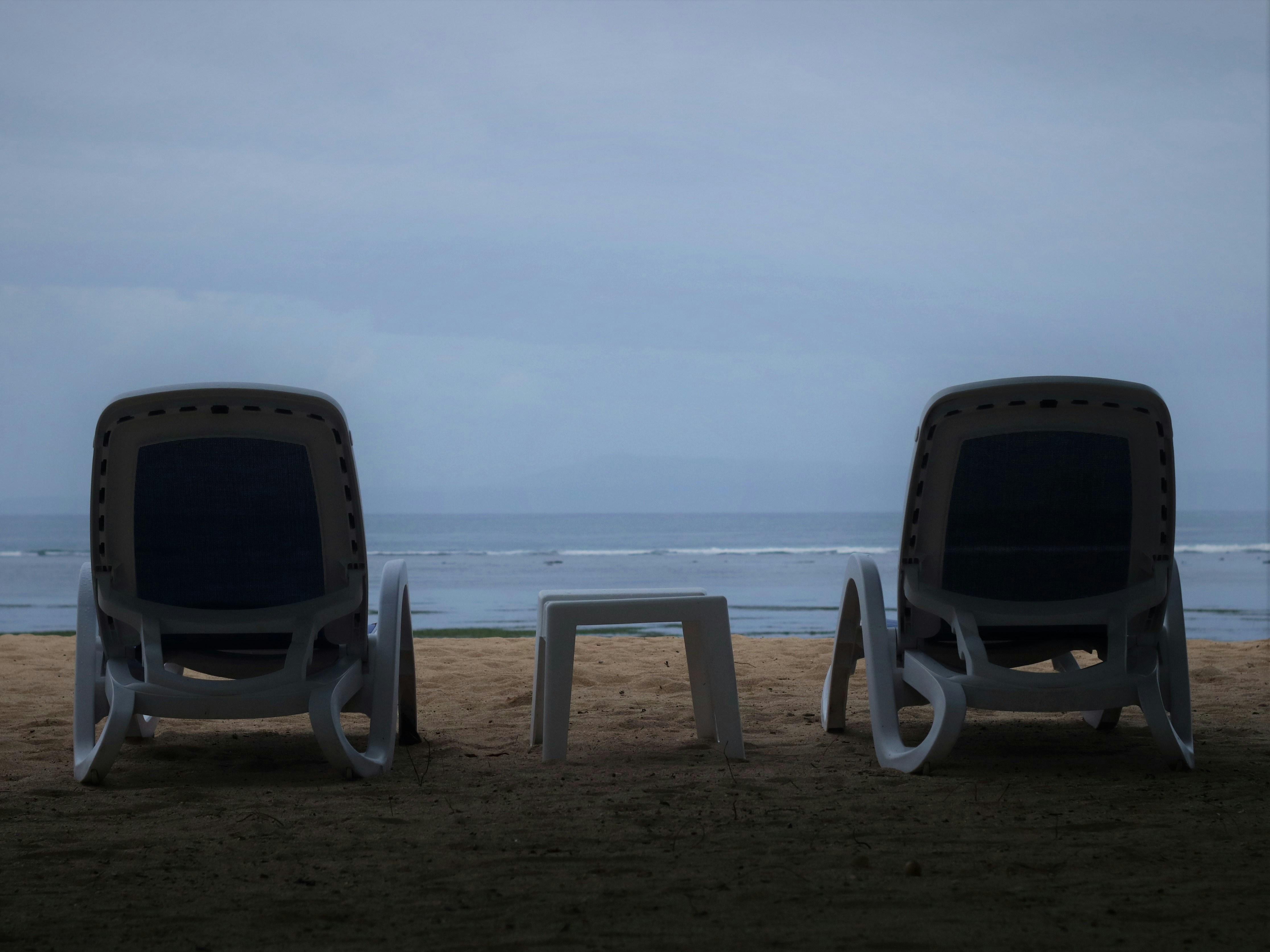 ein paar Stühle sitzen auf einem Sandstrand