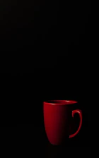 Close-up of a red and black custom mug on a black surface with white and red lighting accents.