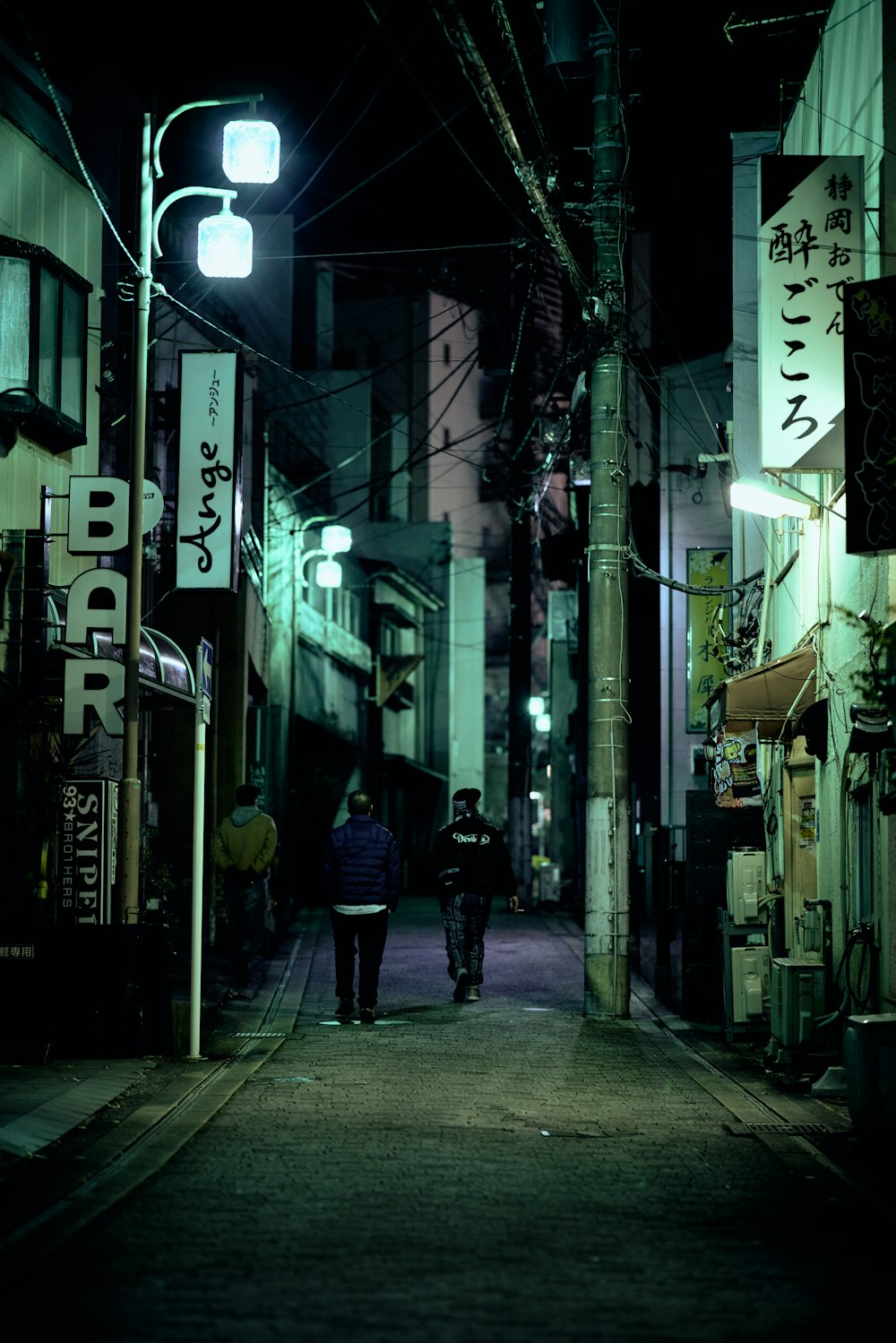 a couple of people walking down a street at night