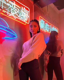 Nighttime urban portrait of a confident individual in layered streetwear, neon lights reflecting.