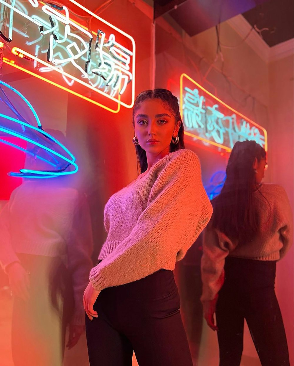 a woman standing in front of a neon sign