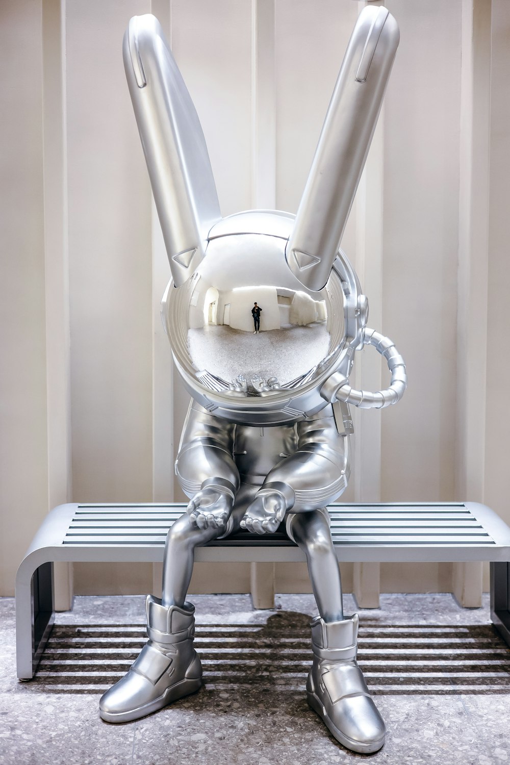 a silver robot sitting on top of a bench