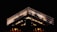 A brightly lit modern building with a prominent grid-like facade stands against a dark night sky. The illumination highlights the structure's architectural details and the text 'GRANTOTEL' is visible on one side of the top.