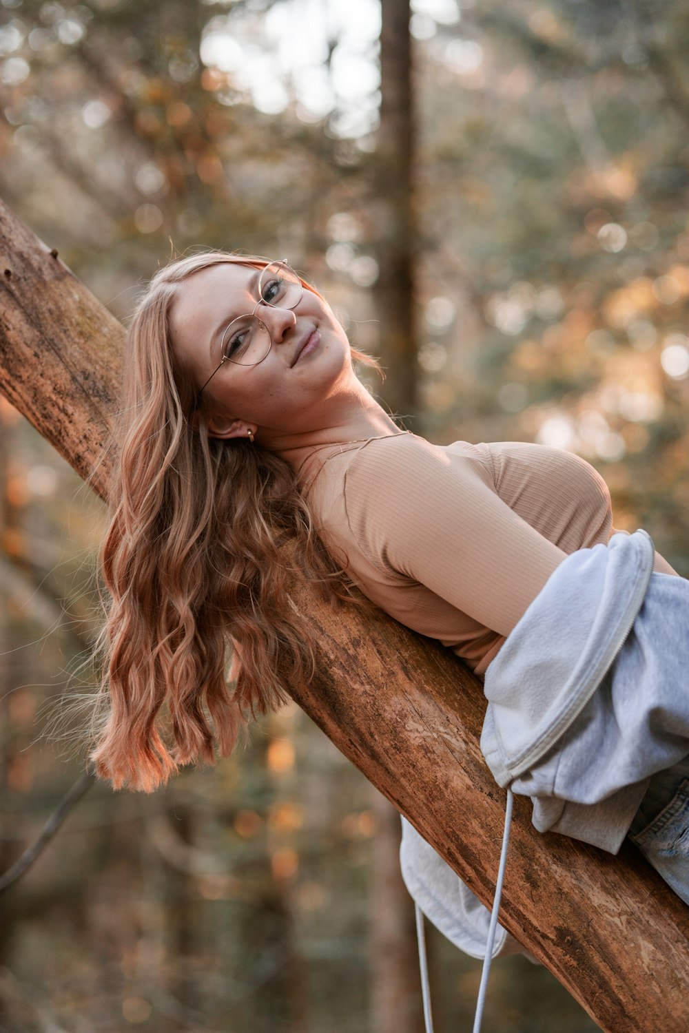 a woman laying on a tree branch in the woods