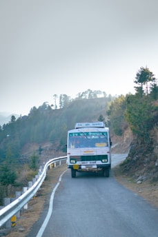 A large, white charter bus driving along a scenic Northern Virginia road.