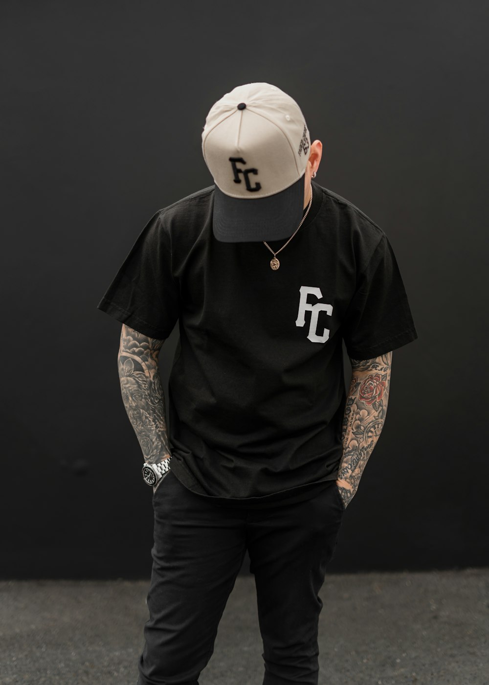 a man with tattoos wearing a black shirt and a hat