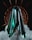 A metallic, futuristic structure with sharp, pointed edges is set against a dark background, surrounded by swirling smoke. The central element displays a glossy sheen with turquoise and black hues reflecting light, while circular, spiked patterns radiate from it.