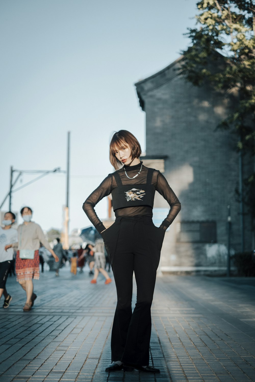 a woman in a black outfit standing on a sidewalk