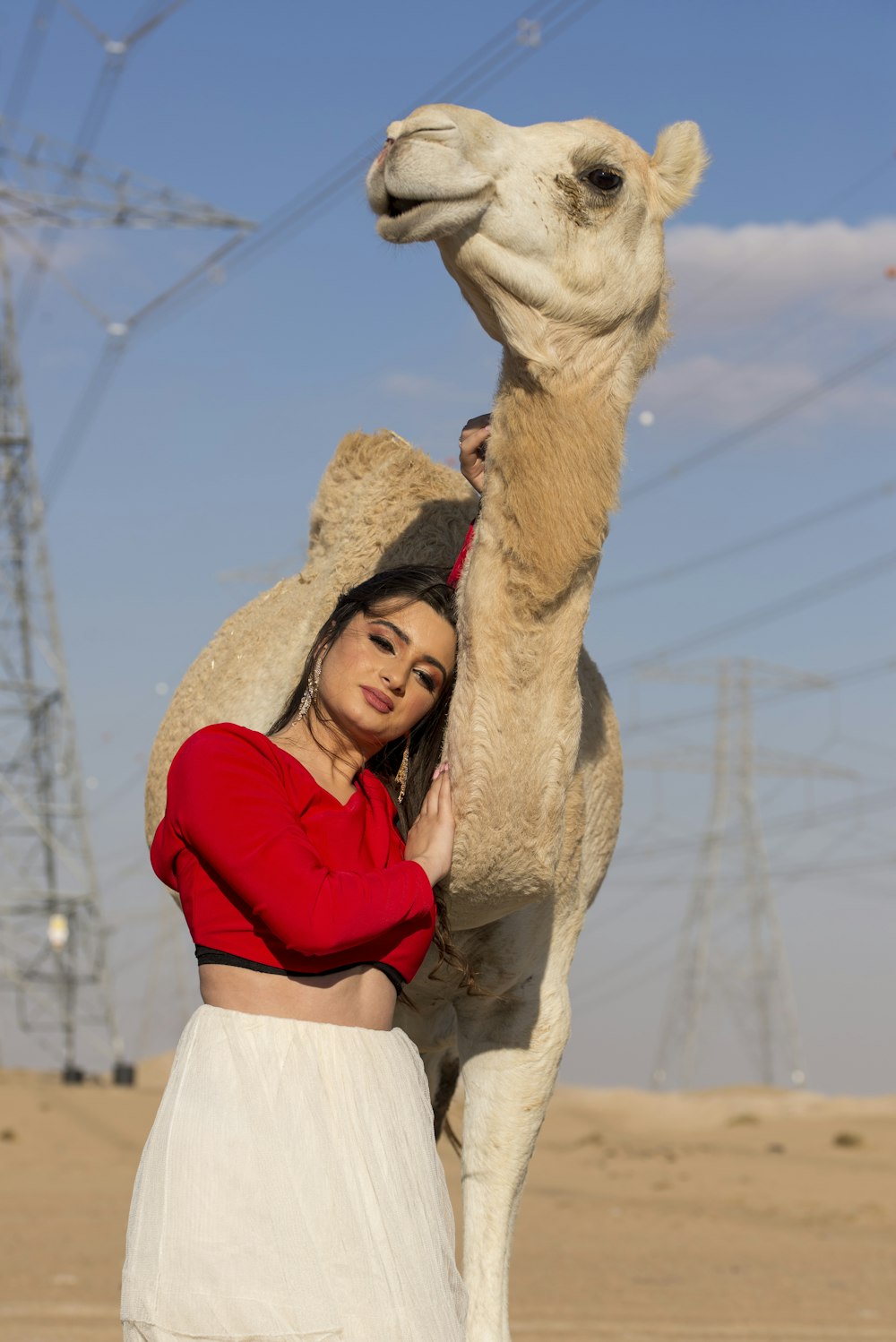 a woman standing next to a camel in the desert