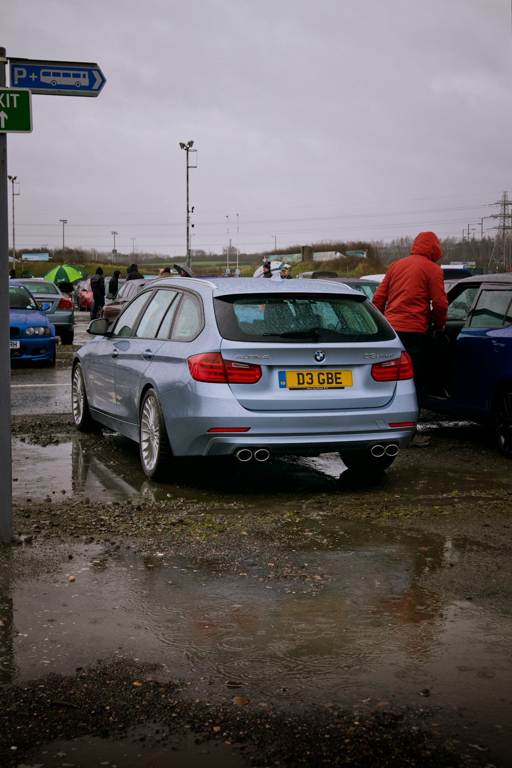 a silver car parked in a parking lot next to a street sign