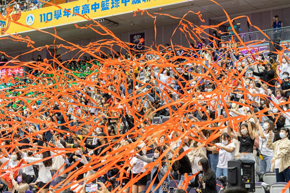 a crowd of people standing around each other holding orange streamers