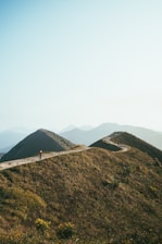 A serene traveler pausing on a winding path surrounded by gentle hills.