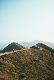 A serene traveler pausing on a winding path surrounded by gentle hills.