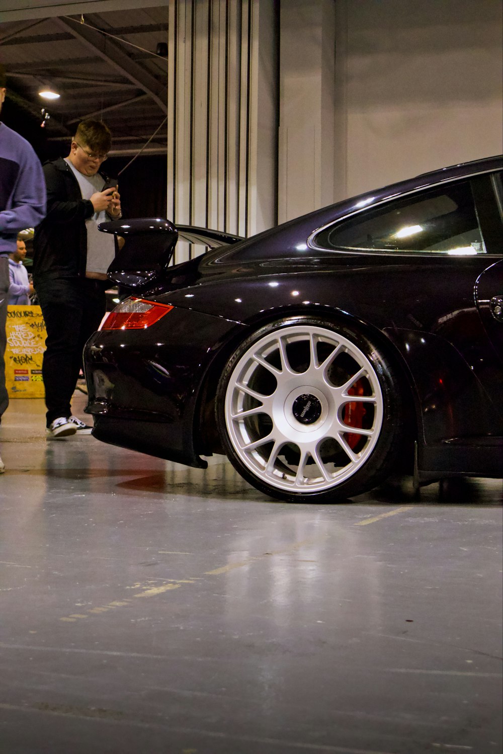 a man standing next to a black car in a garage