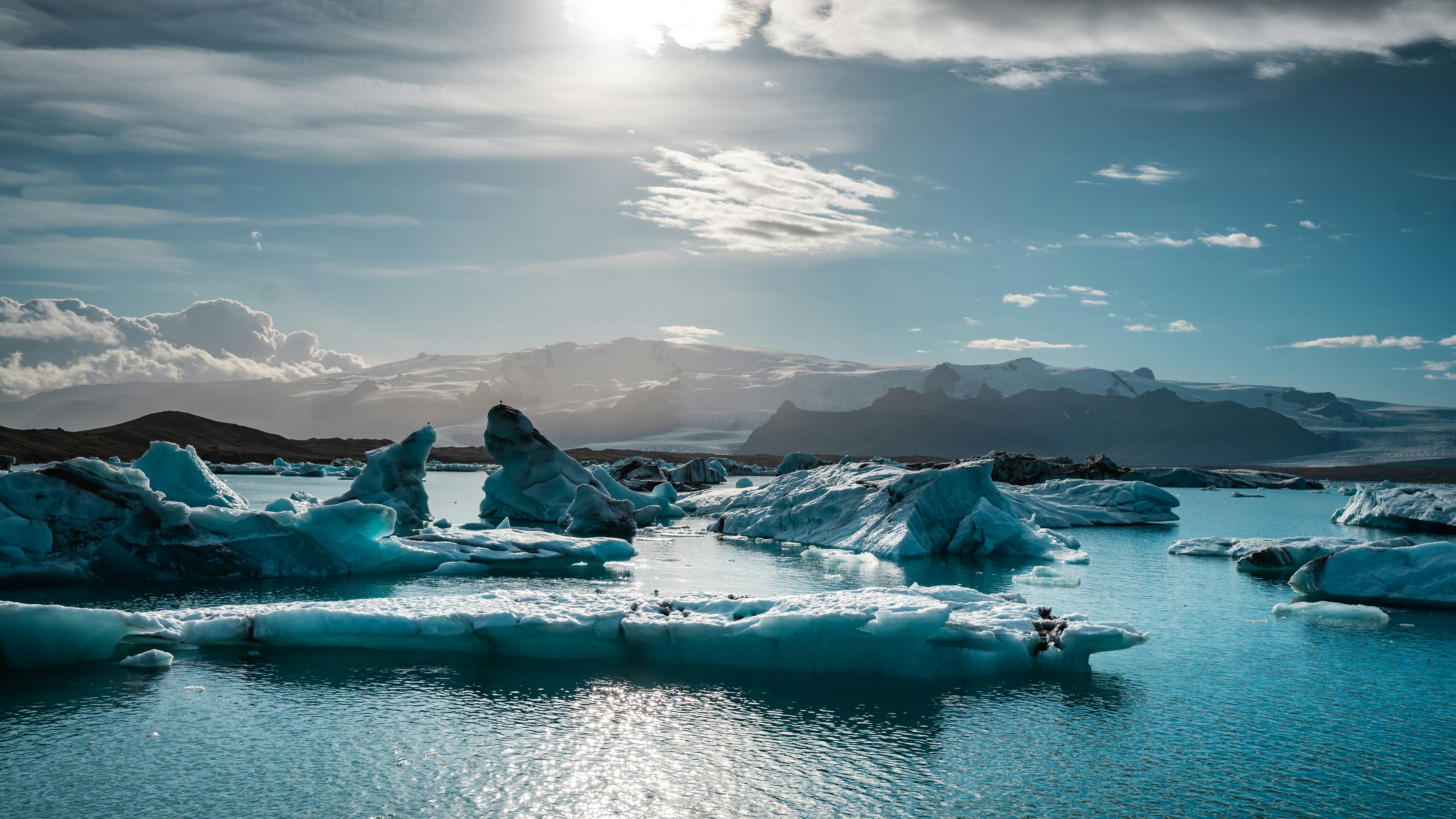 Uno specchio d'acqua circondato da iceberg sotto un cielo nuvoloso