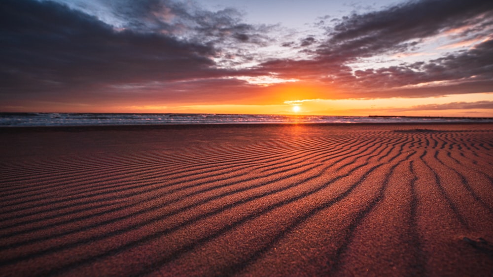 il sole sta tramontando sulla spiaggia e la sabbia è ondulata