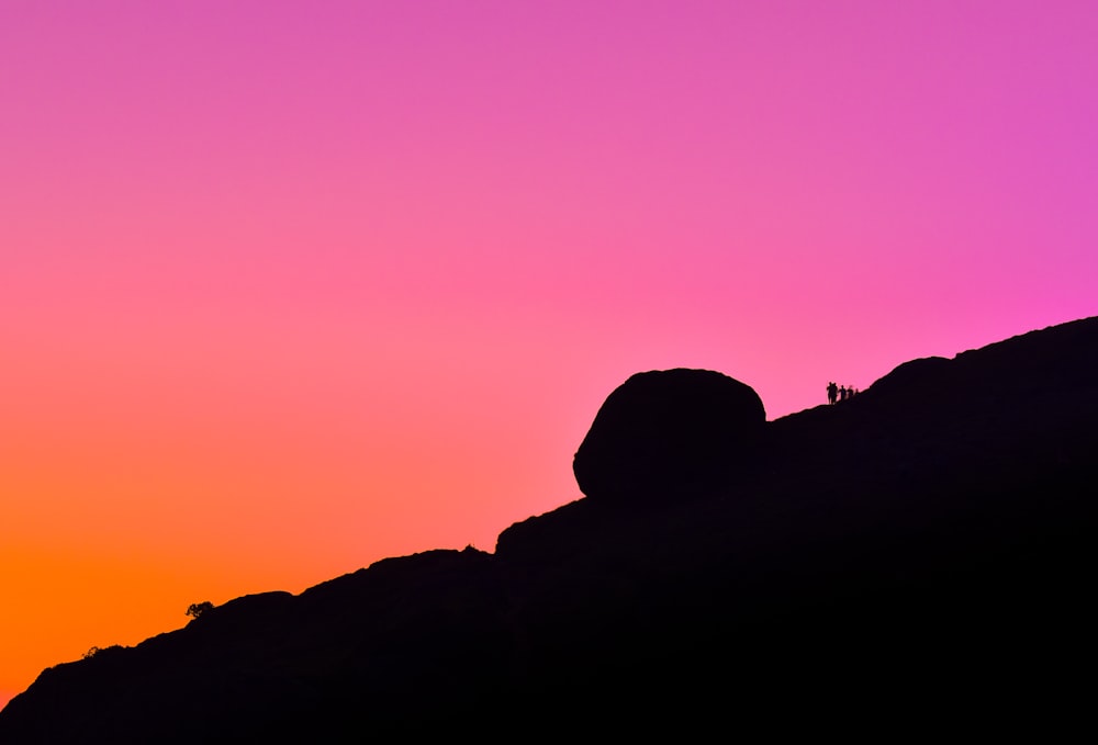 a silhouette of a person standing on top of a hill