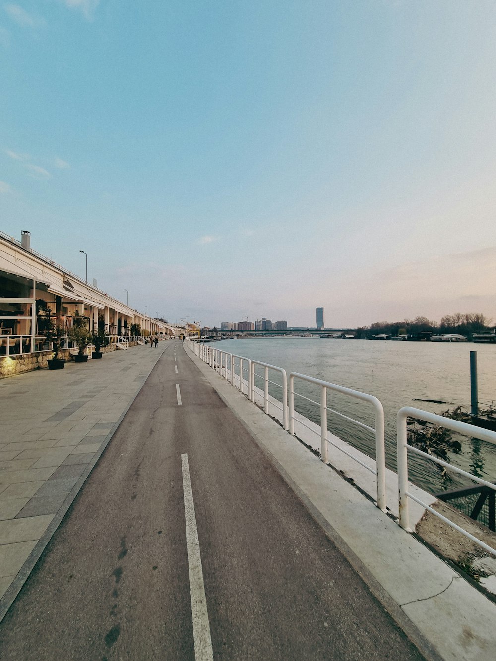 a long empty road next to a body of water