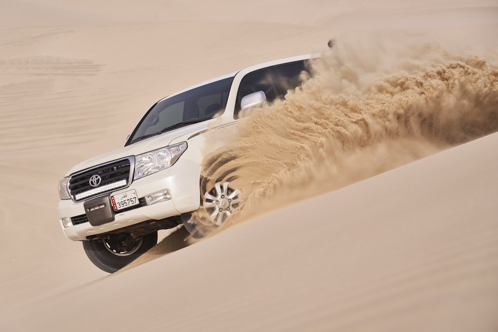 a white truck driving through a sandy area