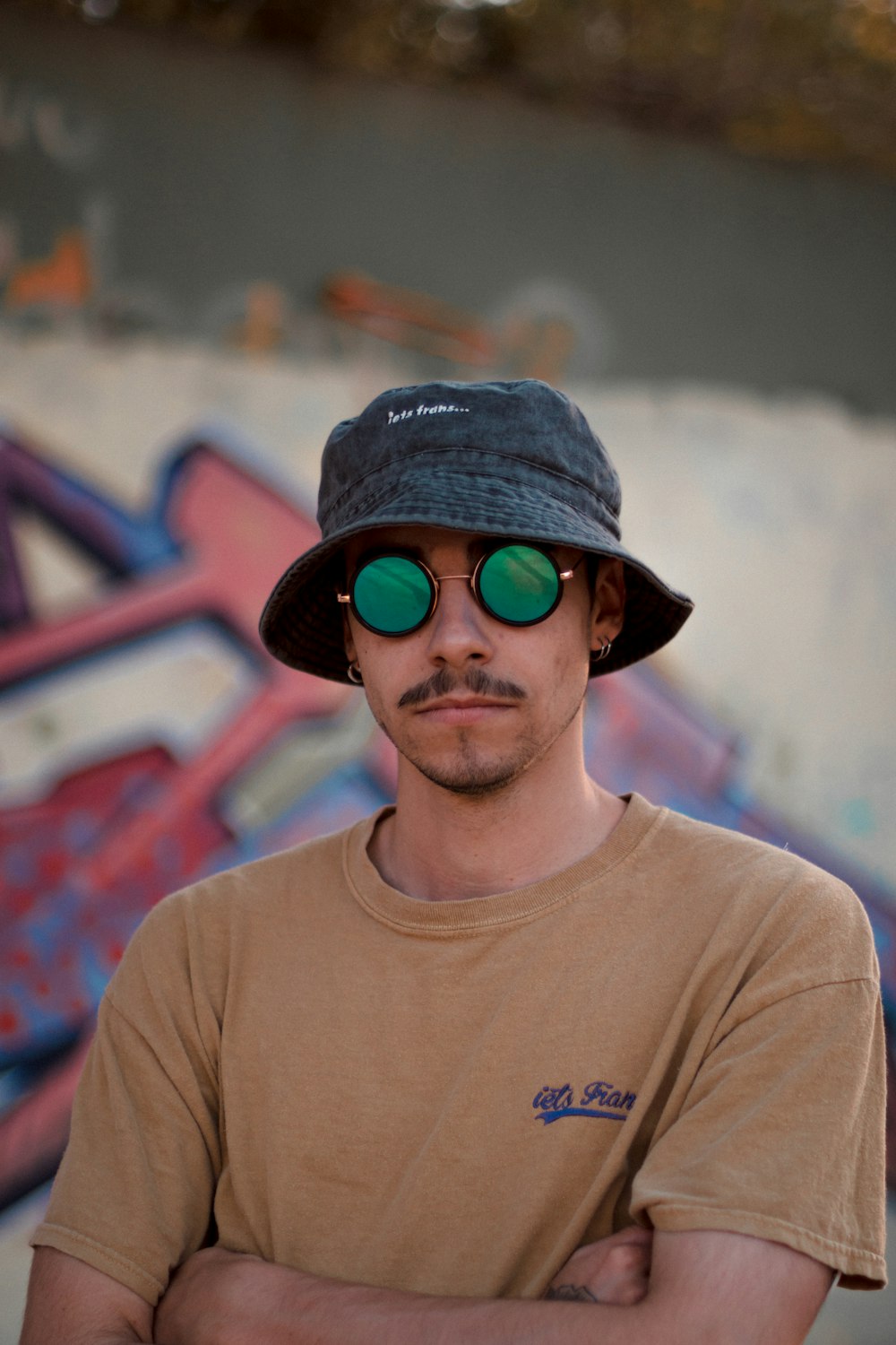 a man wearing a hat and green sunglasses
