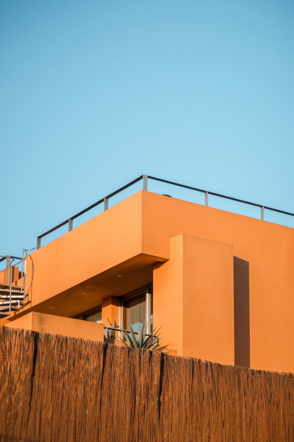 a tall orange building with a balcony and balcony railing