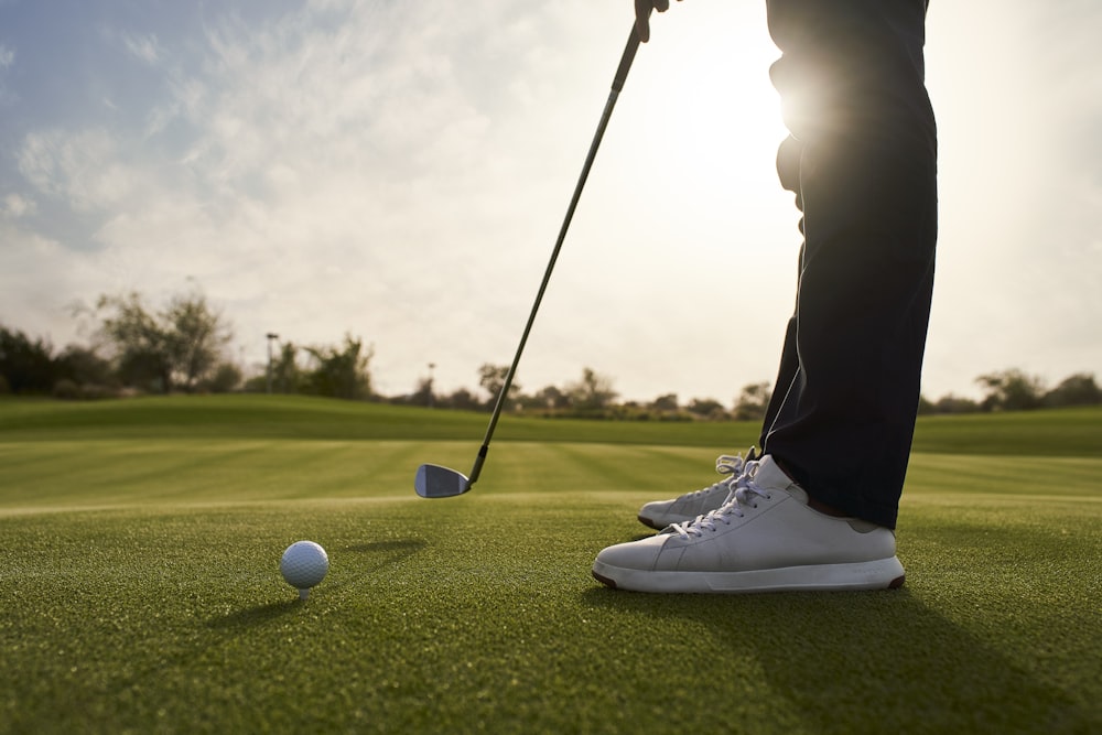 Una persona poniendo una pelota de golf en el green